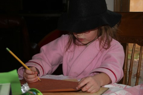 child in a witches hat writing a spell