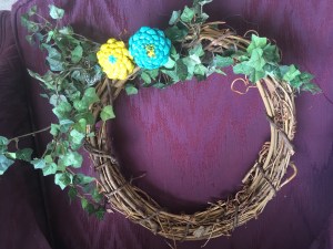 adding greenery to pine cone zinnia wreath